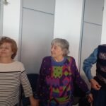 Három egyesületi tag látszik, ahogy állnak és egymás kezét fogják, részt vesznek a táncos játékban