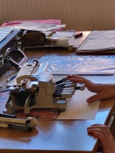 Braille gép közelről, munkatársunk keze látszik, ahogy lenyomja a billentyűt rajta