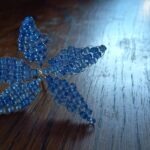 Egy elkészült virág, öt szirma van, lila színű gyöngyből