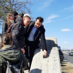 Egy ember kezével tapintja a Rubik-kocka szobrot, a többiek körülötte nézik