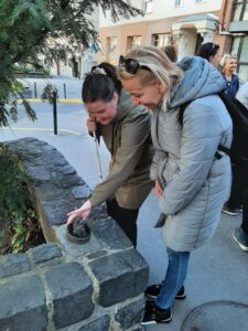 A három kutya egy kosárban szobrot egy résztvwevő kezével tapintja, egy másik nézi
