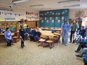 Körben ülnek a gyerekek és többen is éppen a fehérbotos közlekedést róbálják ki Dorka instruálásával