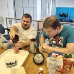 Másik két résztvevő fiatal zöldséget és áfonyát tett a Smoothie készítő gép üvegébe, aminek a tetejét éppen lezárja egyikük