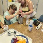 Két résztvevő közösen a helyére illeszti az üveget, indulhat a turmixolás