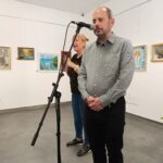 Gangl Tamás, a Siketvakok Országos Egyesületének elnöke beszédet mond, mellette a jeltolmács áll, előtte a közönség ül.