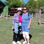 Két résztvevő mosolyogva áll a napsütésben, háttérben a zöld természet.