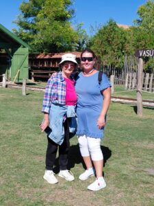 Két résztvevő mosolyogva áll a napsütésben, háttérben a zöld természet.