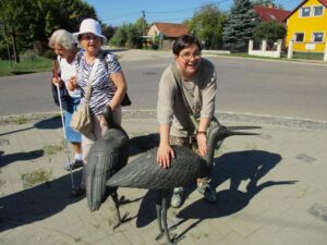 Pár résztvevő a bronzból készült élethű gólyaszobrokat tapintja éppen