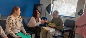 A jeltolmácsolás közelről látszik, a résztvevő ölében a bemutatkozáshoz használt plüssfigura