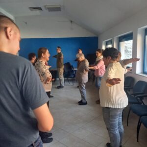 Az oktató elmagyarázza a gyakorlatot a tagoknak ,akik vele szemben állnak oldalra kinyújtott kézzel