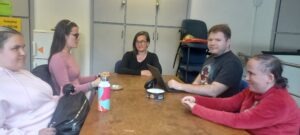 A fiatalok klubján a résztvevők ülnek a nagy teremben és hallgatják a művészetterapeuta önismereti előadását