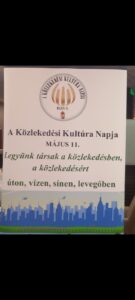 A közlekedési konferencián felállított tábla, mely a közlekedési kultura napja május 11. feliratot, egy felhívást, miszerint legyünk társak a közlekedésben, a közlekedésért, úton , vízen, sínen , levegőben tartalmaz és egyfajta kifejező ábrázolást is