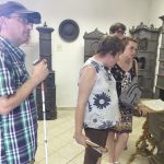 Két tagunk és egy kísérő látszik, ahogy a bemutatóteremben hallgatják az előadást