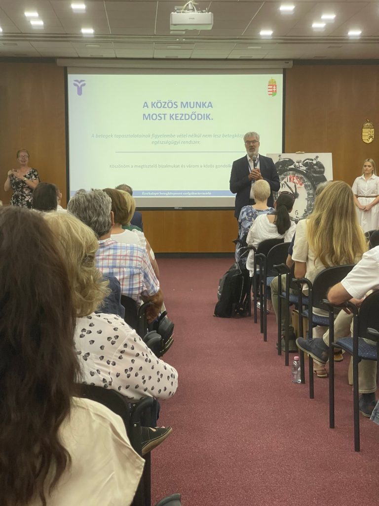 Dr. Kaló Zoltán főigazgató egy kivetített diakép előtt, amin az a felirat olvasható, A KÖZÖS MUNKA MOST KEZDŐDIK!